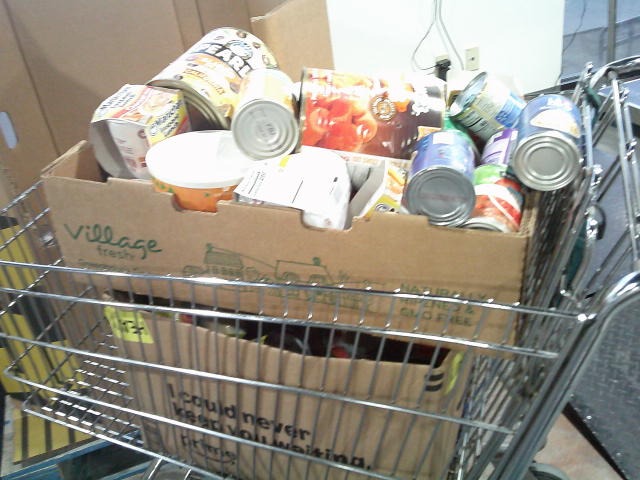 Produce tray and amazon box filled with food in a shopping cart.